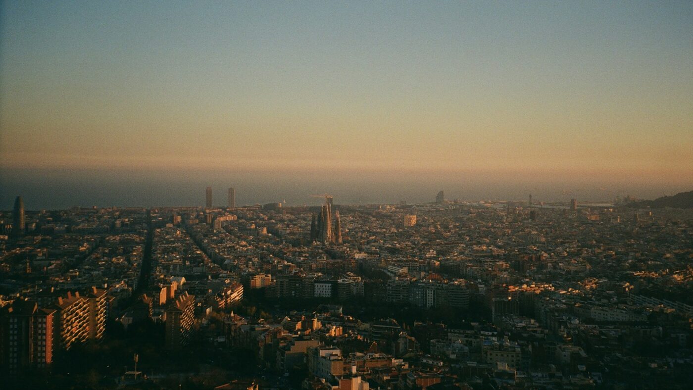 Barcelona seen from the hills at sunset, with the Eixample stretching down to the sea