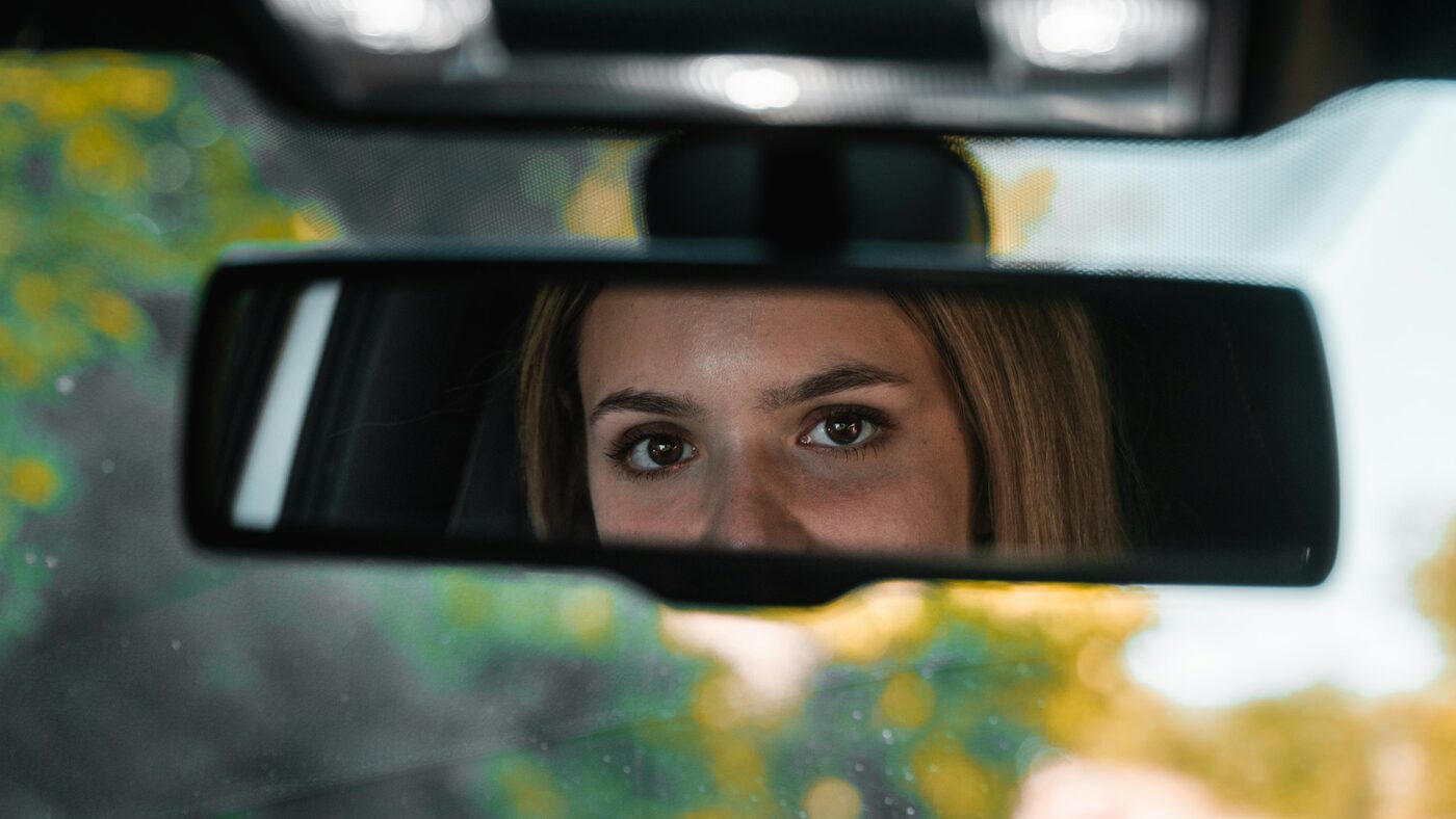 A woman's eyes reflected in the rear-view mirror of a car